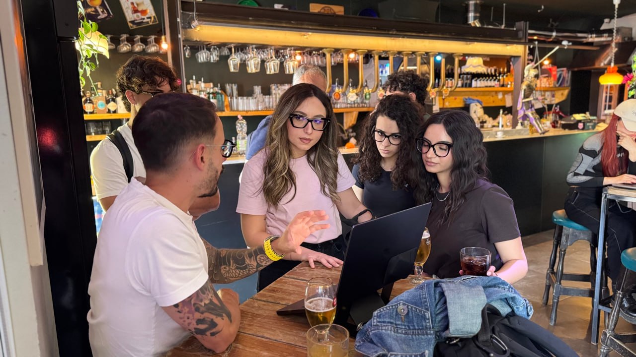 Partecipanti discutono davanti a un laptop al bancone del bar